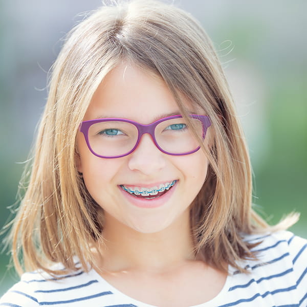 A smiling girl with eyeglasses is wearing braces